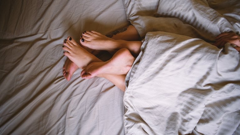 Symbolbild Genitalherpes: Füße von einem Paar im Bett.