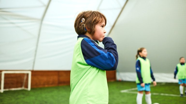 Ein Junge trägt ein Cochlea-Implantat beim Fußballtraining