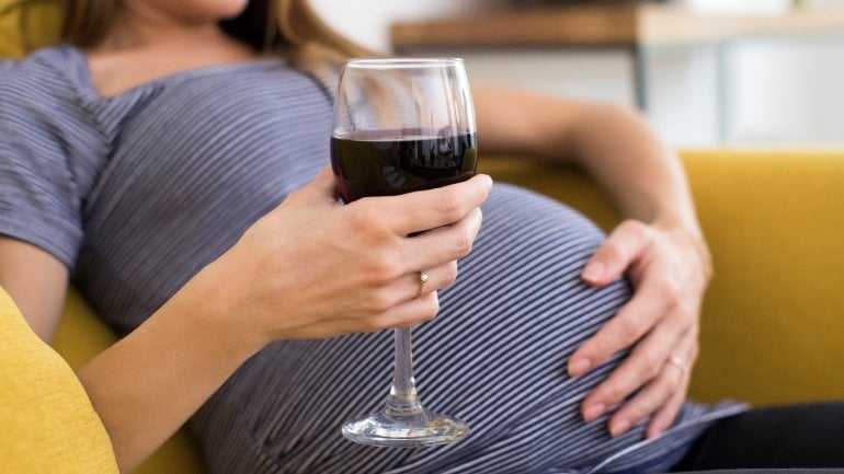 Frau trinkt während der Schwangerschaft Alkohol, was Ursache des Fetalen Alkoholsyndroms ist.