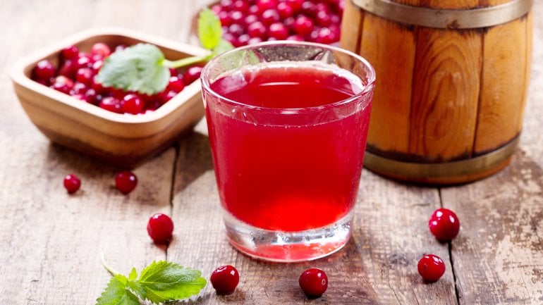 Ein Glas Cranberrysaft und Schalen mit den Beeren stehen auf einem Tisch