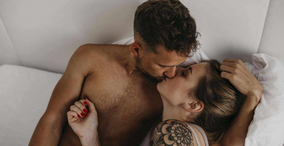 Ein junges Paar küsst sich im Bett