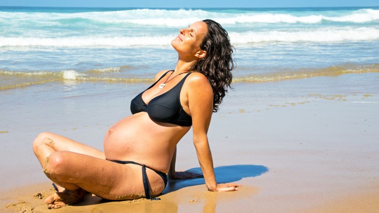 Schwangere Frau im Bikini am Strand.