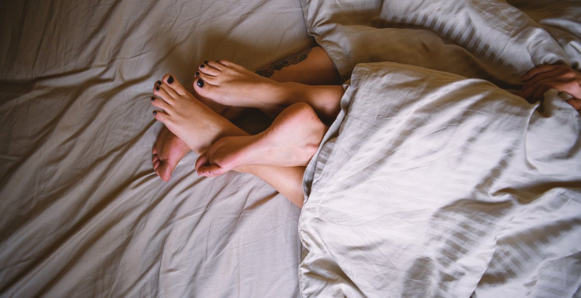 Symbolbild Genitalherpes: Füße von einem Paar im Bett.