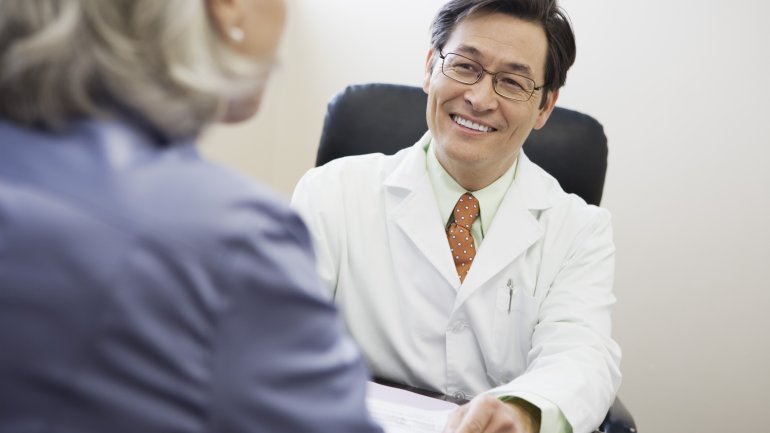 Ein lächelnder Arzt im Gespräch mit einer Patientin.