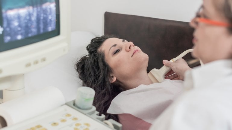 Ärztin untersucht die Schilddrüse einer Frau mit Ultraschall