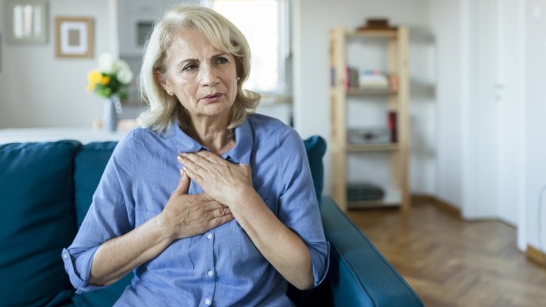Frau mit Roemheld-Syndrom hält sich schmerzende Brust.