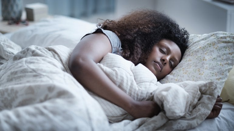 Eine Frau schläft mit Schlafapnoe im Bett.