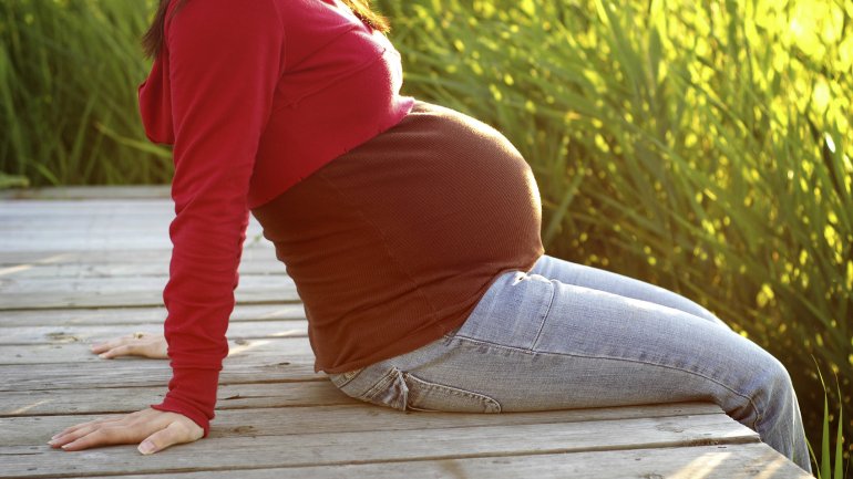 Eine Schwangere in Umstandskleidung auf einem Steg.