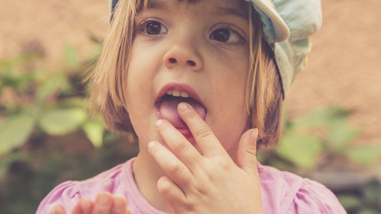 Ein Mädchen steckt sich einen Finger in den Mund