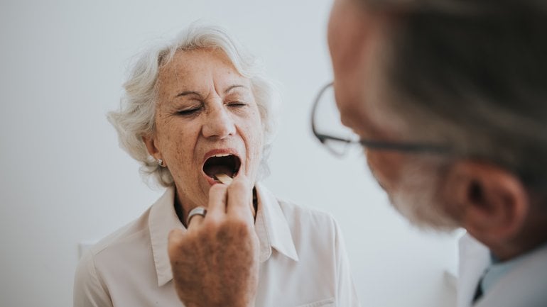Frau mit Zungenkrebs wird ärztlich untersucht.