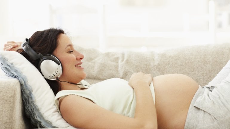 Eine Schwangere entspannt mit Kopfhörern.