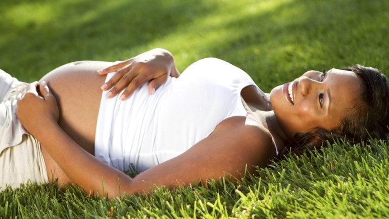 Schwangere entspannt auf einer Wiese.