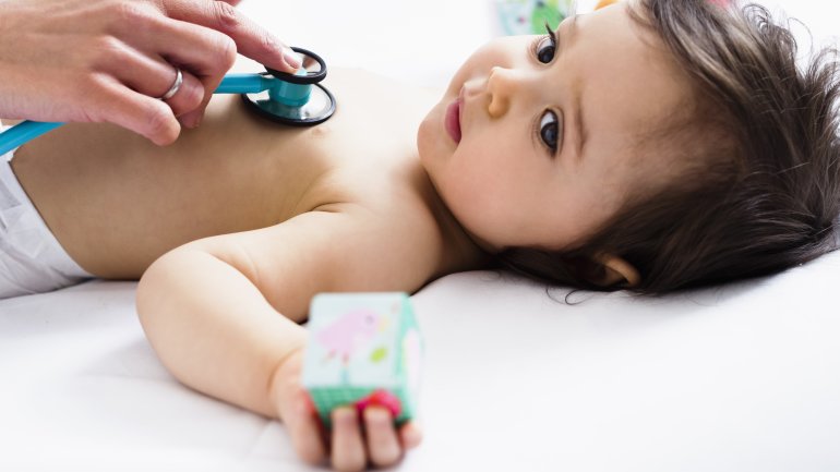 Ein Kleinkind mit RS-Virus wird mit dem Stethoskop abgehört.