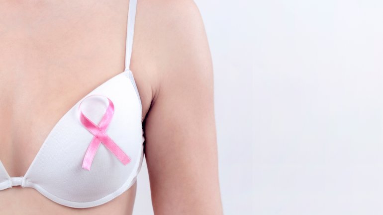 Mastektomie ist oft Folge von Brustkrebs: Frau mit BH und rosa Schleife macht darauf aufmerksam.