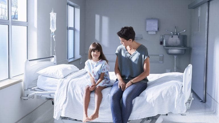 Eine Mutter und ihr Kind sitzen auf einem Bett im Krankenhaus.