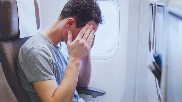 Flugangst: Ein Mann sitzt im Flugzeug und fühlt sich unwohl.