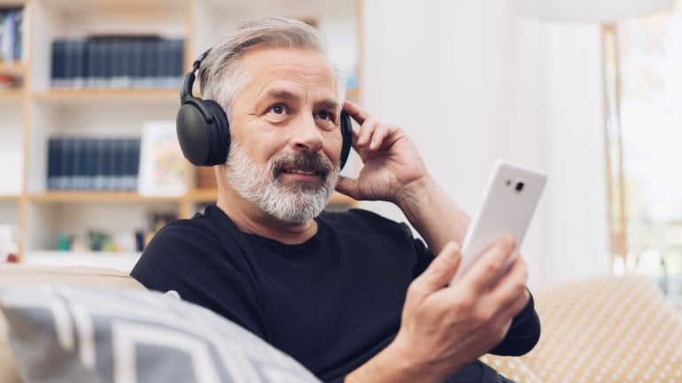 Mann sitzt auf Sofa mit Kopfhörern und benutzt die Kalmeda Tinnitus-App.