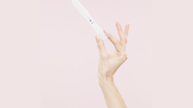 Eine Frauenhand hält einen positiven Schwangerschaftstest