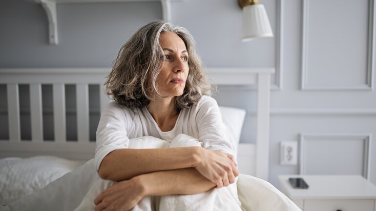Frau in den Wechseljahren im Bett mit Schlafproblemen