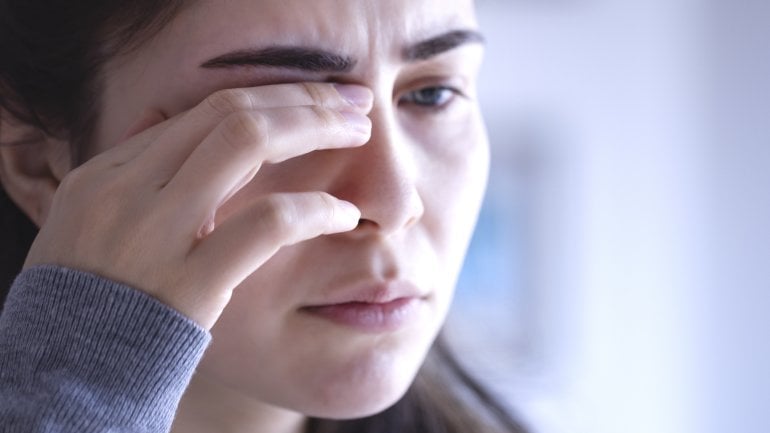 Lederhautentzündung: Frau reibt ihre Augen und hat Schmerzen