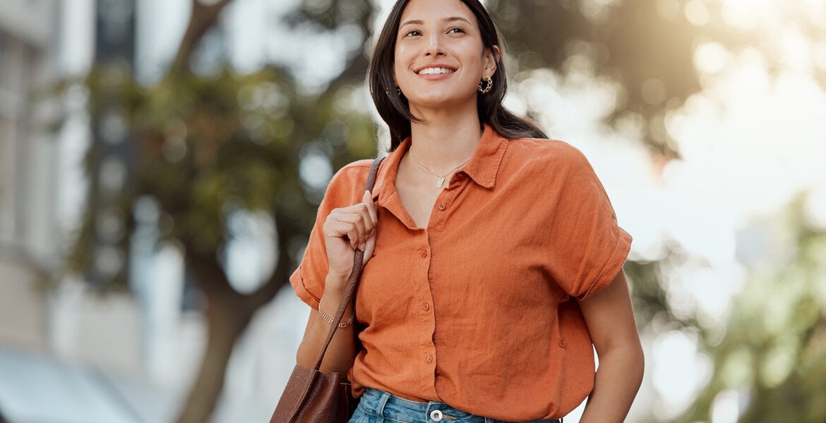 Eine junge Frau spaziert glücklich in einer Stadt.