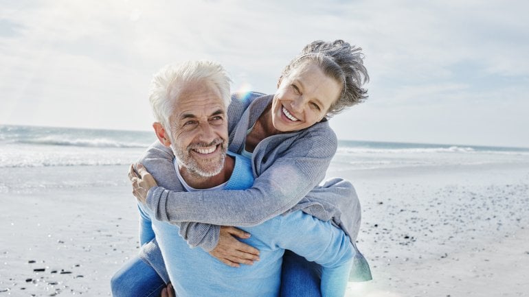Bild eines älteren Ehepaars, das am Strand ist.