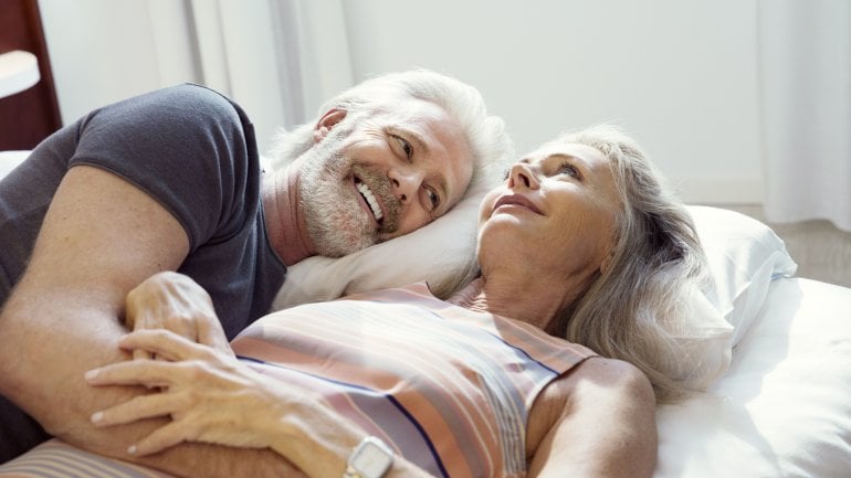 Vasektomie: Glückliches älteres Paar liegt zusammen im Bett
