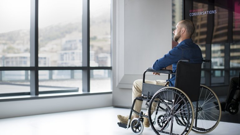 Ein Mann sitzt im Rollstuhl und schaut aus dem Fenster.