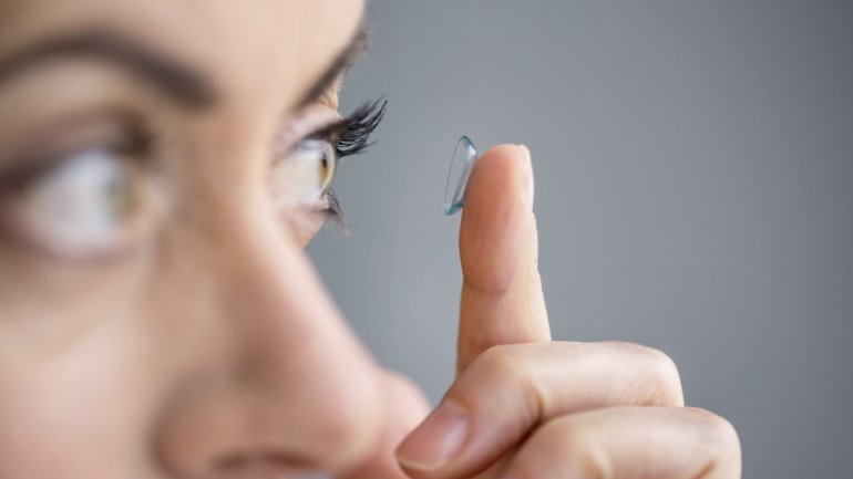 Das Bild zeigt eine Frau, die eine Kontaktlinse einsetzt.