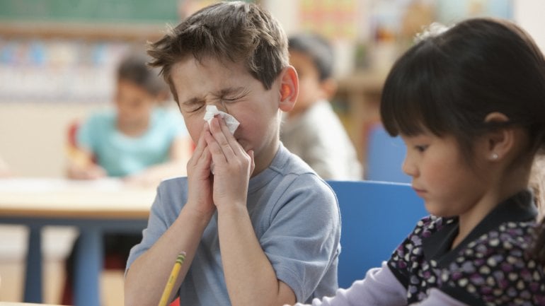 Ein Kind in der Schule putzt sich die Nase