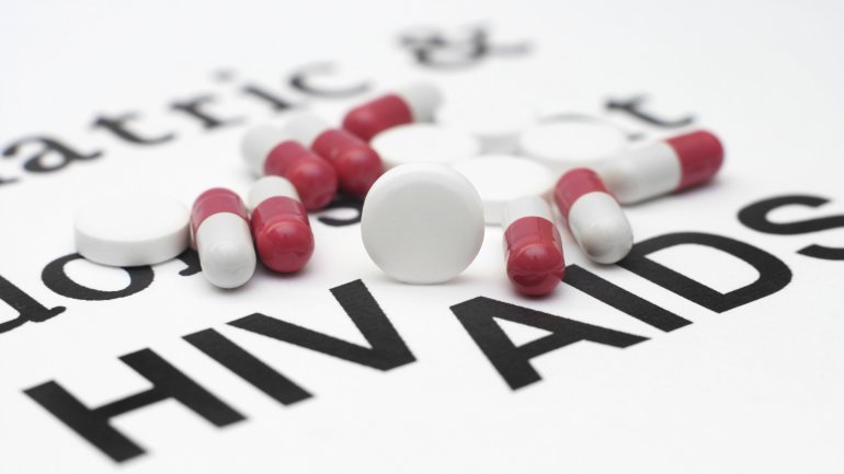 Ein Zettel, auf dem HIV und AIDS steht, darauf befinden sich Tabletten.