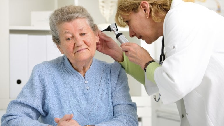 Eine Ärztin schaut in das Ohr einer älteren Patientin.