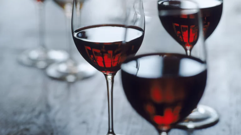 Das Bild zeigt Gläser, die mit Rotwein zur Hälfte gefüllt sind.