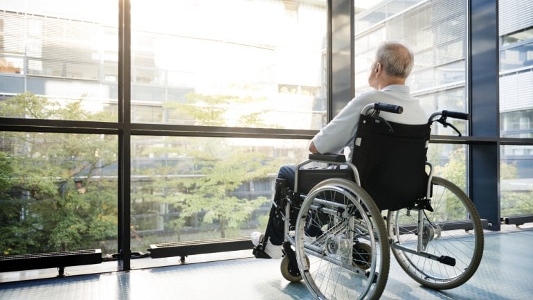 Das Bild zeigt einen älteren Mann im Rollstuhl