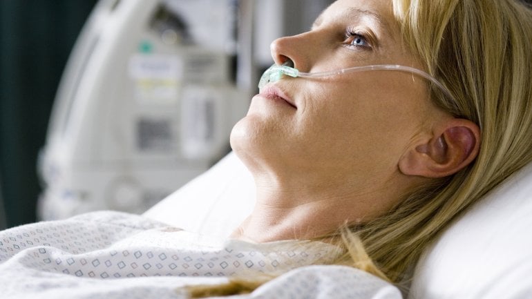 Eine Frau liegt im Krankenhausbett und wird über die Nase beatmet