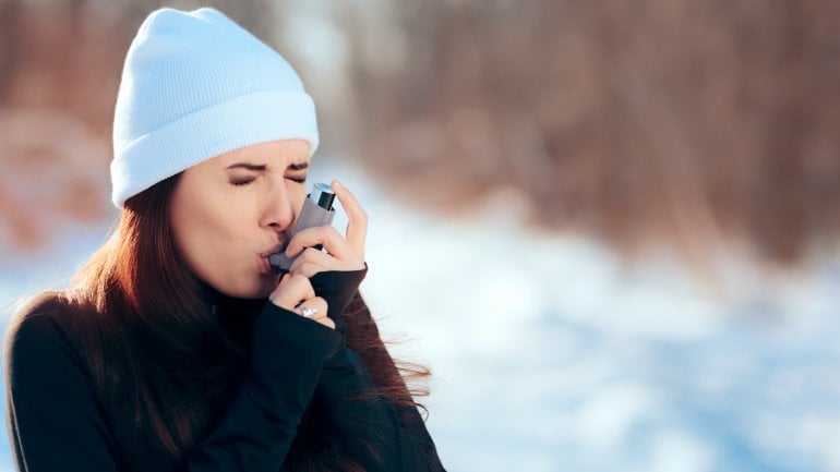 Frau im Winter draußen mit Asthmaspray