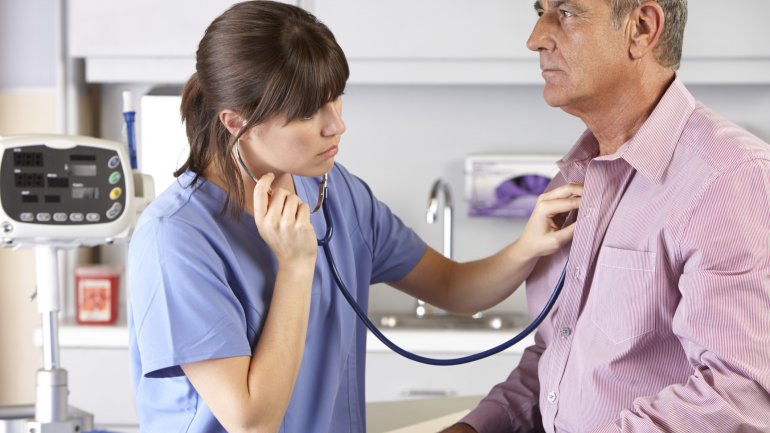 Eine Ärztin hört einen Mann mit einem Stethoskop ab.