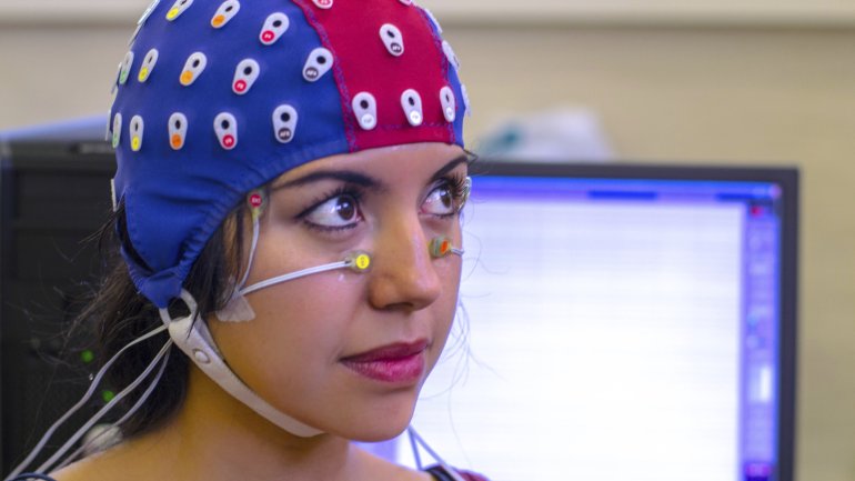 Das Bild zeigt eine Frau mit einer EEG-Haube auf dem Kopf-