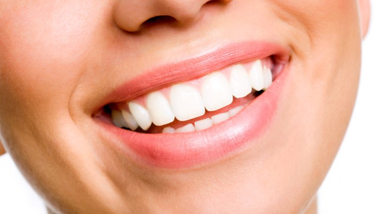 Das Lächeln einer jungen Frau mit strahlen weißen, geraden Zähnen.