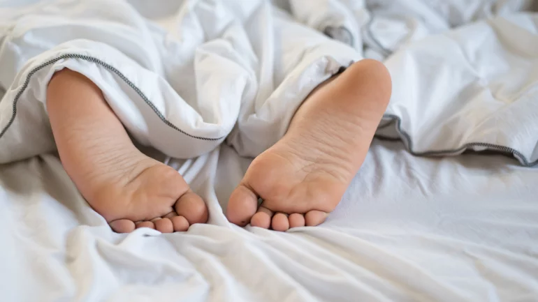 Füße im Bett: Person leidet unter brennenden Füßen.