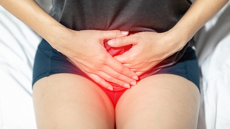 Frau hält sich Hände vor geröteten Intimbereich.