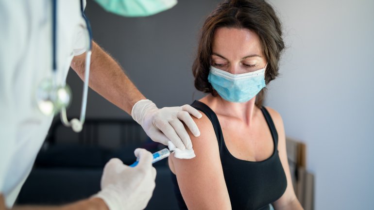 Frau mit Maske erhält Corona-Impfung