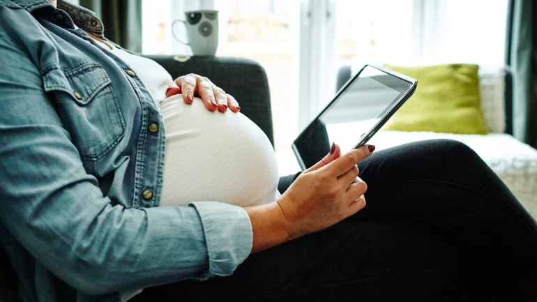 Eine Hochschwangere mit Tablet.
