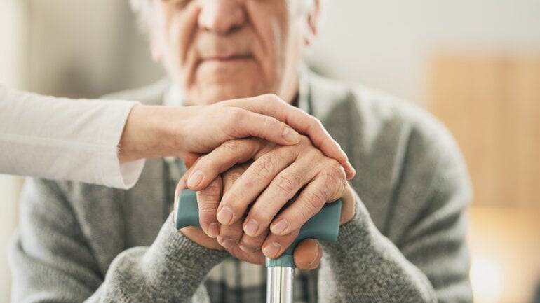 Frau hält Hand ihres alten Vaters
