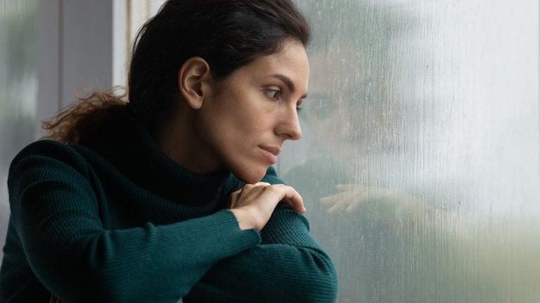 Eine Frau schaut traurig aus dem Fenster.
