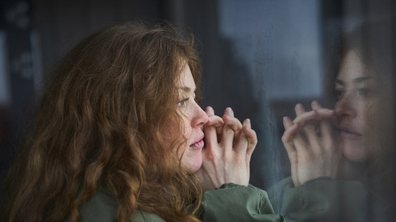 Eine Frau blickt traurig aus dem Fenster.