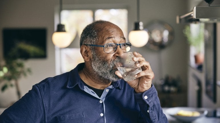 Mann mit Diabetes insipidus trinkt ein Glas Wasser.