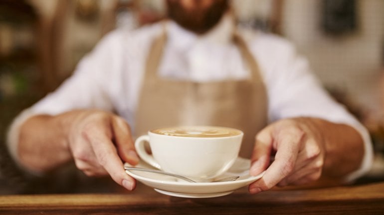 Das Bild zeigt einen Barista mit einer Tasse Kaffee.