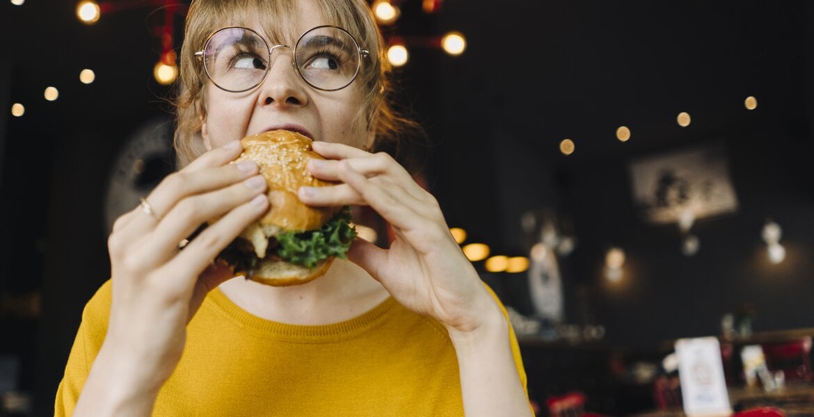 Divertikulose: Frau isst einen Hamburger im Restaurant