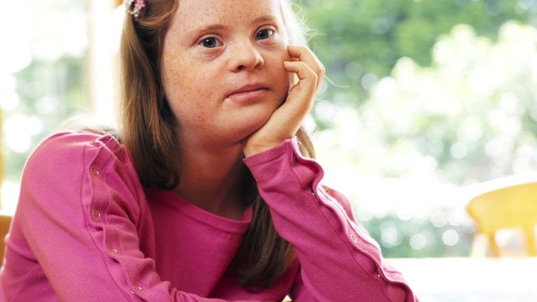 Das Bild zeigt ein Mädchen mit Down-Syndrom. 